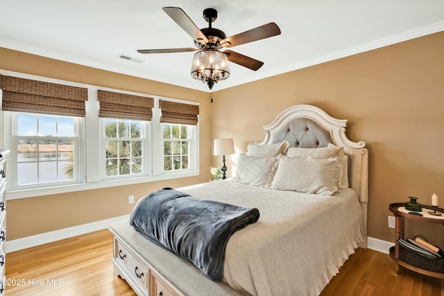 bedroom featuring ceiling fan, light wood-type flooring, and ornamental molding