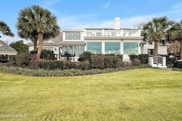 rear view of property with a balcony and a lawn