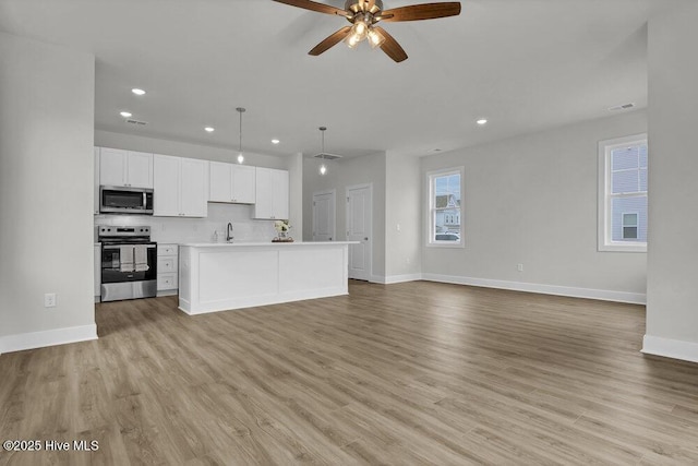 unfurnished living room with sink, light wood-type flooring, and ceiling fan