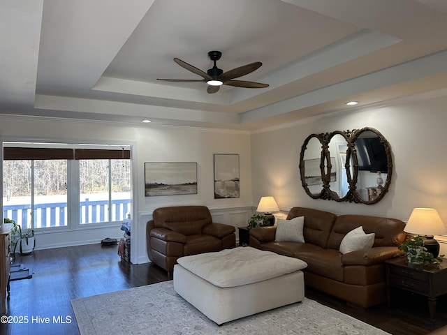 living room featuring a raised ceiling, ceiling fan, and dark wood-type flooring