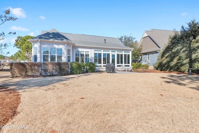 rear view of house featuring a yard, a patio, and a sunroom