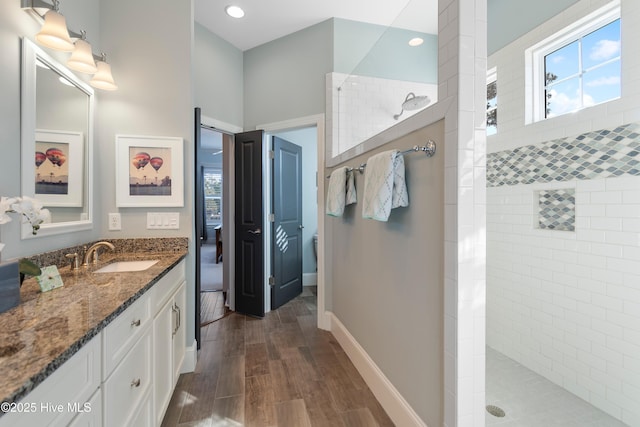 bathroom featuring vanity, wood-type flooring, a healthy amount of sunlight, and a tile shower