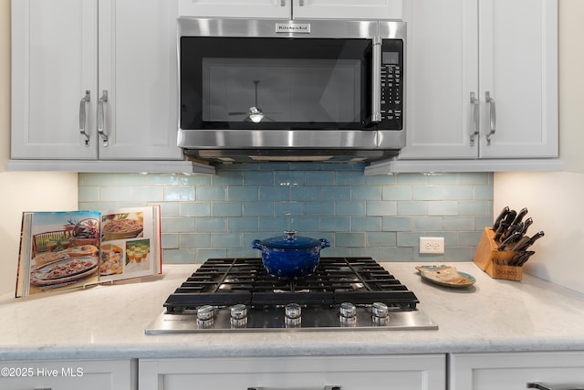 kitchen featuring white cabinetry, stainless steel appliances, light stone counters, and tasteful backsplash