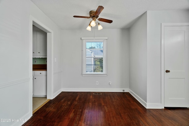 unfurnished room with ceiling fan, a textured ceiling, and dark hardwood / wood-style floors