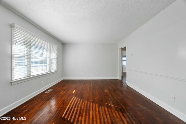 empty room with dark hardwood / wood-style flooring and a textured ceiling