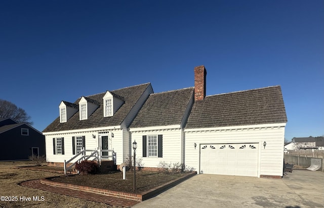 new england style home with driveway, a chimney, and an attached garage