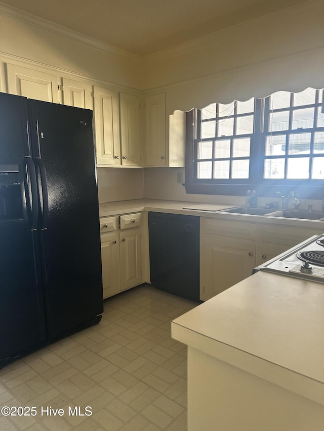 kitchen with crown molding, black appliances, light countertops, and white cabinets