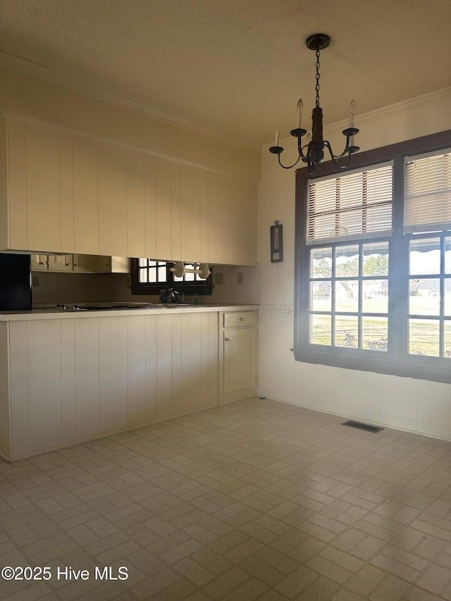 kitchen with a chandelier, visible vents, white cabinets, brick patterned floor, and crown molding