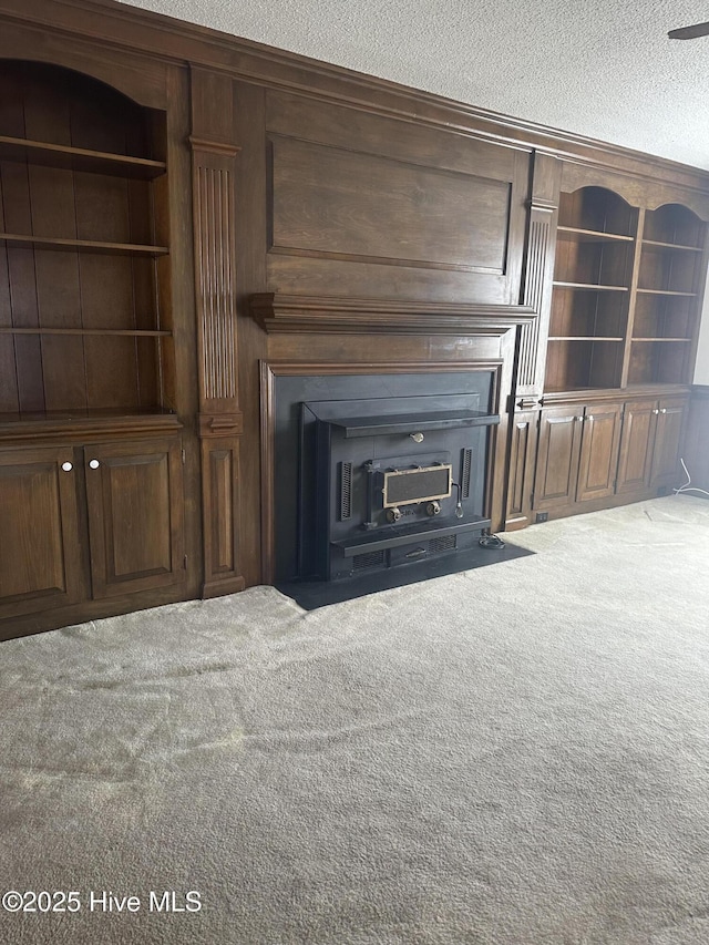 unfurnished living room featuring built in shelves, a textured ceiling, and carpet flooring