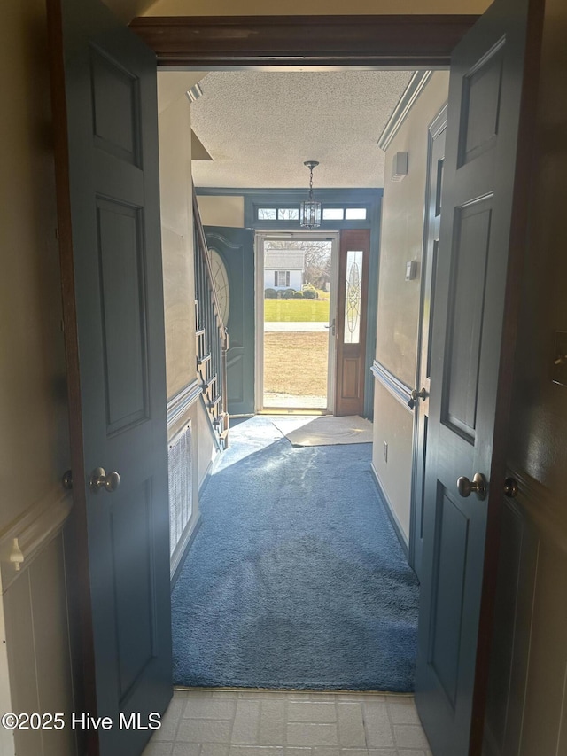 doorway to outside with stairway, light carpet, a decorative wall, and a textured ceiling