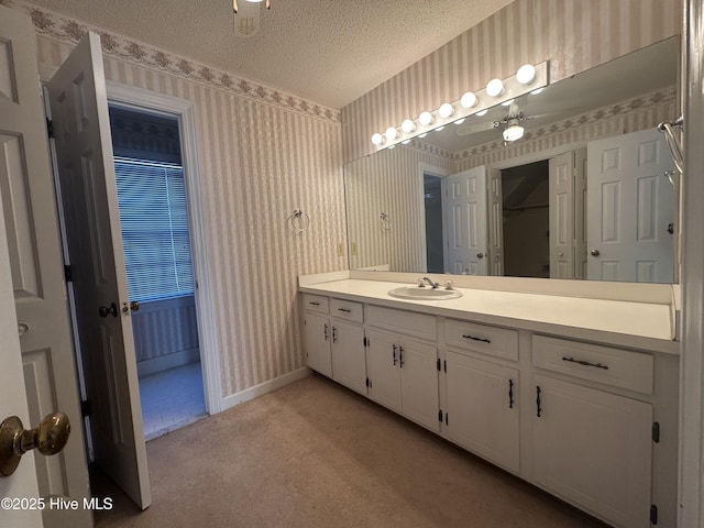 bathroom featuring wallpapered walls, baseboards, a textured ceiling, and vanity