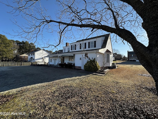 view of front of home with central AC, a chimney, and gravel driveway