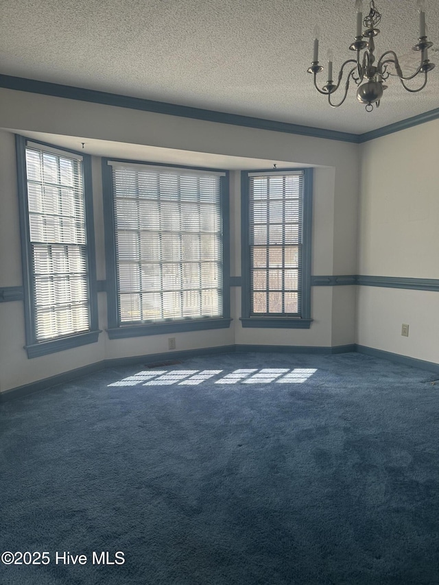 carpeted spare room featuring a chandelier, ornamental molding, a textured ceiling, and baseboards