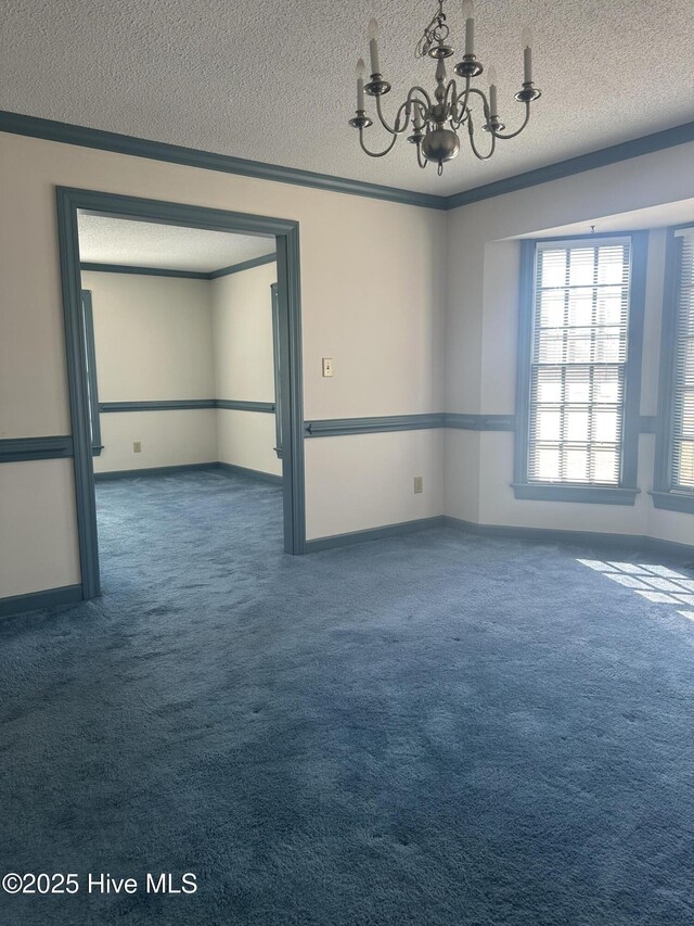 carpeted empty room featuring baseboards, a textured ceiling, a chandelier, and crown molding