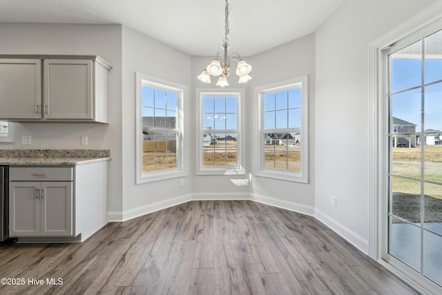 unfurnished dining area featuring an inviting chandelier and light wood-type flooring