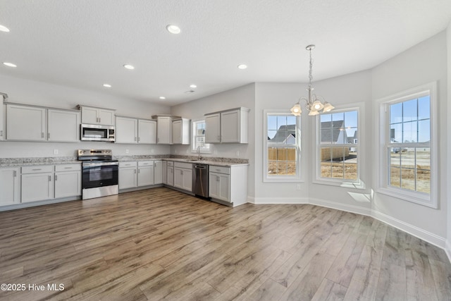 kitchen featuring sink, light hardwood / wood-style flooring, stainless steel appliances, decorative light fixtures, and a chandelier