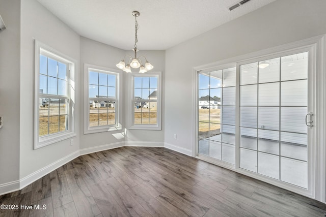 unfurnished dining area featuring hardwood / wood-style floors, a textured ceiling, and a notable chandelier