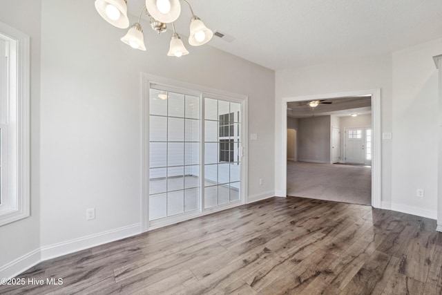 unfurnished room featuring hardwood / wood-style flooring and ceiling fan with notable chandelier