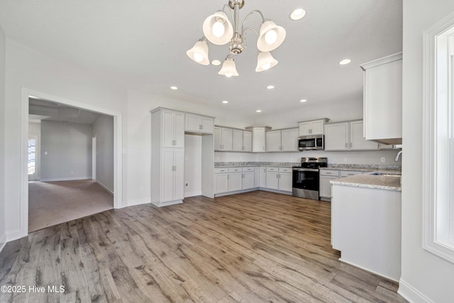 kitchen with sink, decorative light fixtures, stainless steel appliances, light hardwood / wood-style floors, and white cabinets