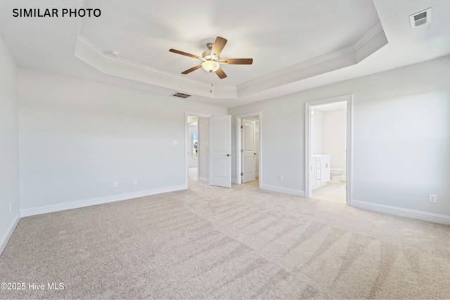 unfurnished bedroom featuring light colored carpet, ornamental molding, connected bathroom, and a raised ceiling