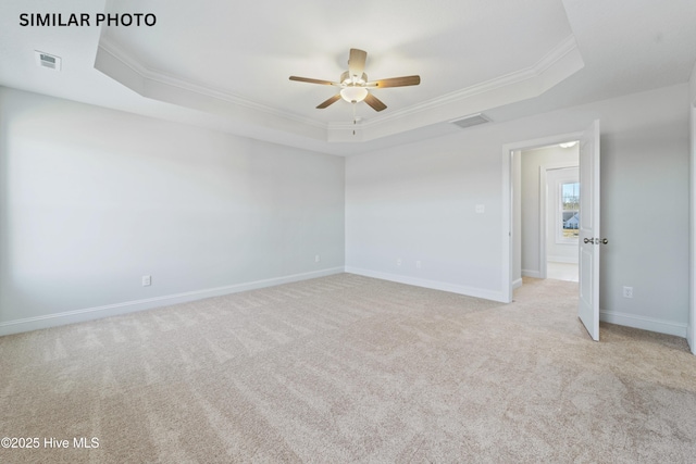 empty room featuring light carpet, ornamental molding, a raised ceiling, and ceiling fan