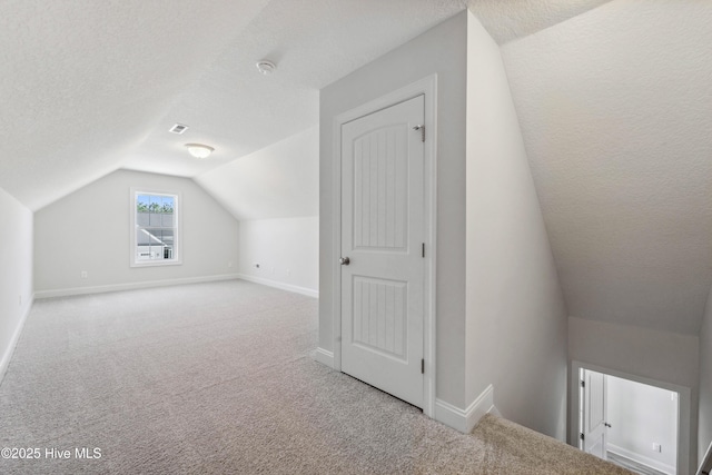 additional living space featuring lofted ceiling, light colored carpet, and a textured ceiling