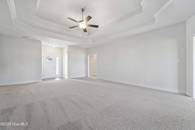 carpeted spare room with ceiling fan, ornamental molding, and a tray ceiling