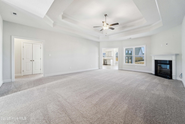 unfurnished living room with light carpet, ornamental molding, a raised ceiling, and ceiling fan