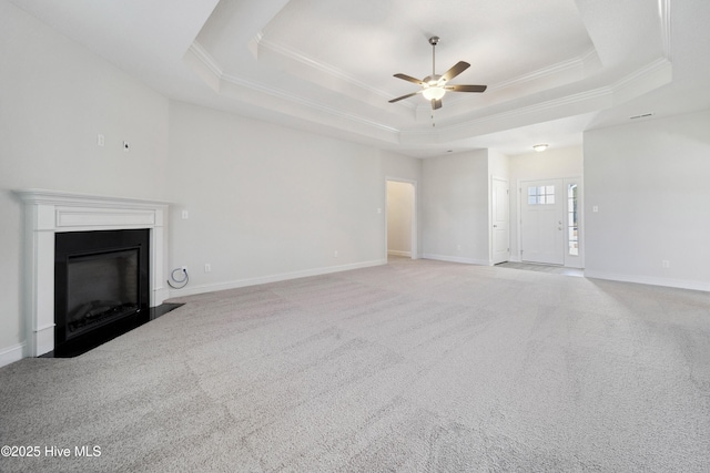 unfurnished living room with ornamental molding, light colored carpet, ceiling fan, and a tray ceiling