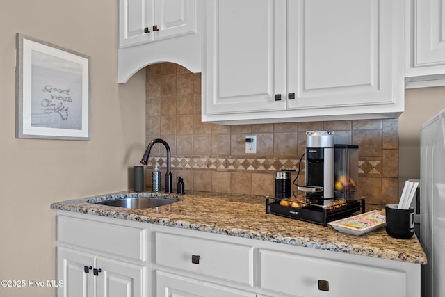 kitchen featuring tasteful backsplash, sink, light stone countertops, and white cabinets