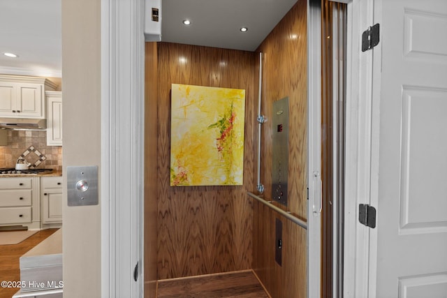 room details with tasteful backsplash, stainless steel gas stovetop, and elevator