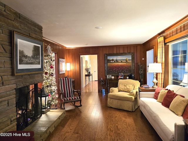 living room featuring a fireplace, wood walls, crown molding, and hardwood / wood-style floors