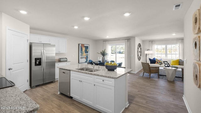 kitchen with white cabinets, appliances with stainless steel finishes, a kitchen island with sink, and sink