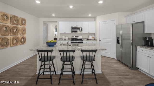 kitchen featuring appliances with stainless steel finishes, a center island with sink, and white cabinetry