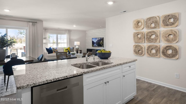 kitchen featuring light stone countertops, stainless steel dishwasher, dark wood-type flooring, sink, and white cabinets