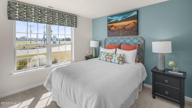 bedroom with light colored carpet and multiple windows