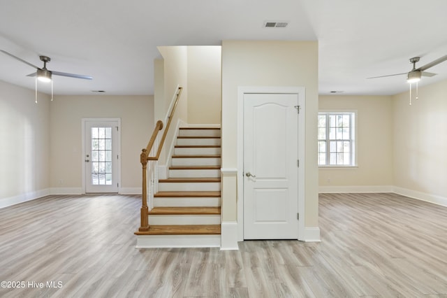 staircase with ceiling fan, plenty of natural light, and hardwood / wood-style flooring