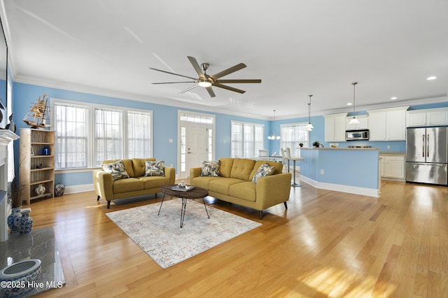 living room with ceiling fan, a premium fireplace, light hardwood / wood-style floors, and ornamental molding