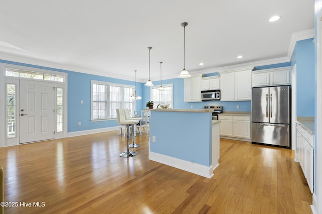 kitchen featuring decorative light fixtures, stainless steel appliances, a kitchen island, white cabinetry, and ornamental molding