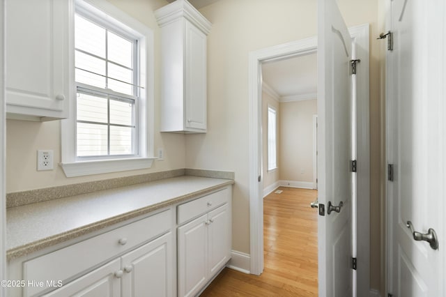 corridor featuring a healthy amount of sunlight, ornamental molding, and hardwood / wood-style flooring