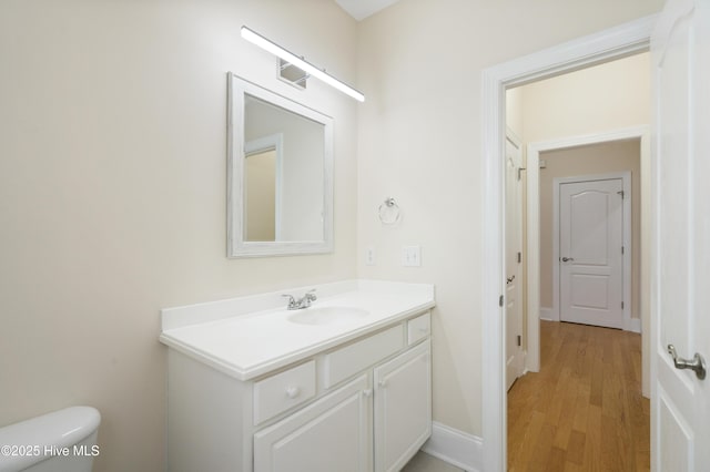 bathroom featuring toilet, wood-type flooring, and vanity