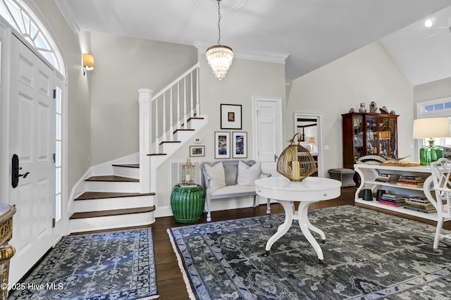 entryway with vaulted ceiling, dark wood-type flooring, ornamental molding, and an inviting chandelier