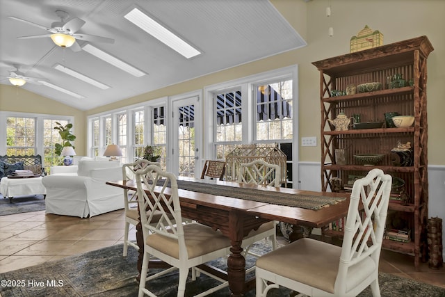 dining area featuring ceiling fan, lofted ceiling with skylight, and tile patterned floors