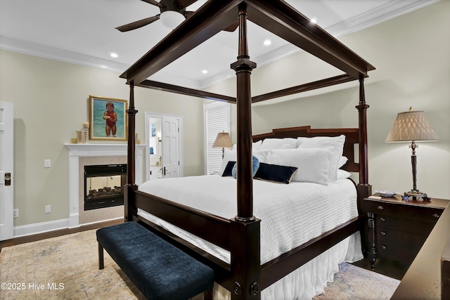 bedroom featuring ceiling fan, hardwood / wood-style floors, beamed ceiling, a multi sided fireplace, and ornamental molding