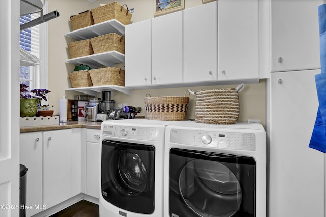 clothes washing area featuring washer and dryer and cabinets