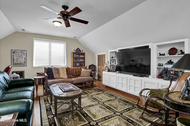 living room featuring hardwood / wood-style flooring, built in shelves, ceiling fan, and vaulted ceiling