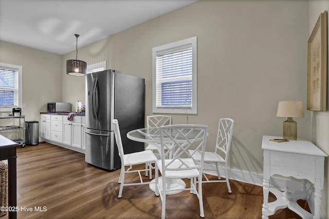 kitchen featuring white cabinetry, dark wood-type flooring, hanging light fixtures, and stainless steel refrigerator