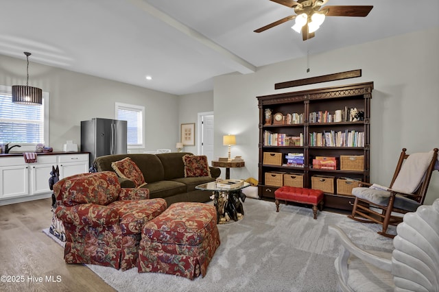 living room featuring ceiling fan, sink, light hardwood / wood-style flooring, and beamed ceiling