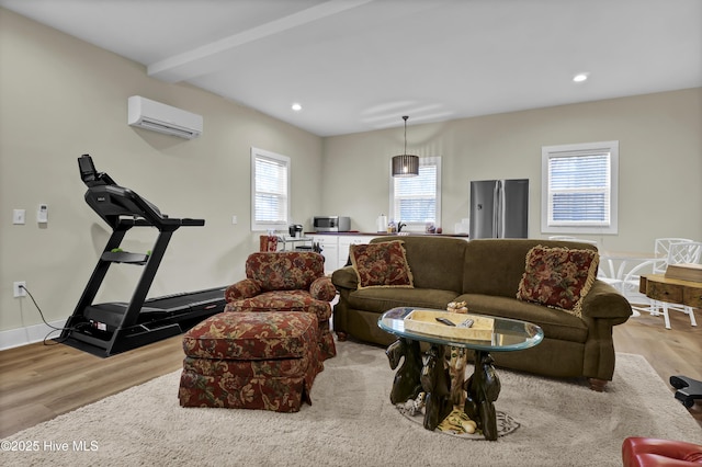 living room with light wood-type flooring, an AC wall unit, and beamed ceiling