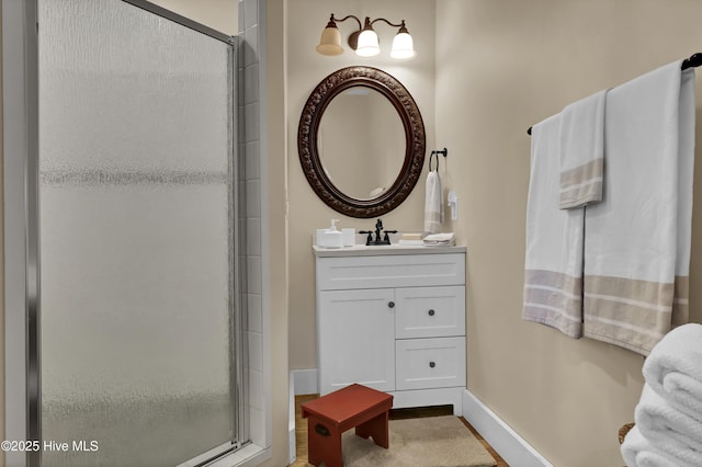 bathroom featuring a shower with shower door and vanity